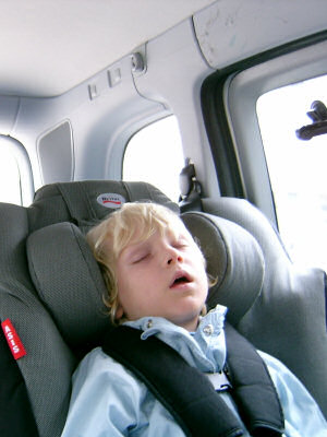Kind schläft im Autositz. 